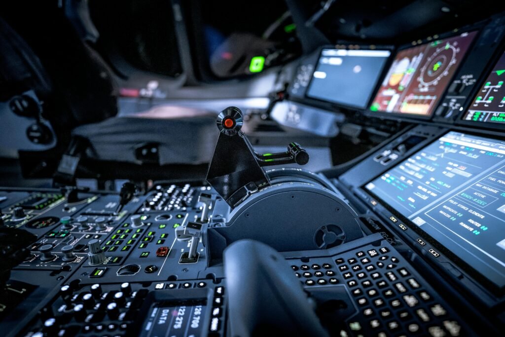 Close-up view of a modern aircraft cockpit with glowing control panels and screens.